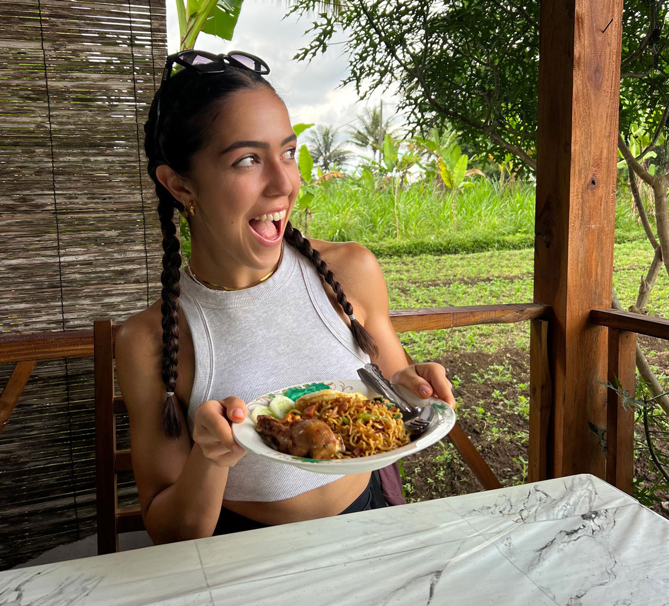 Entrenadora sentada al aire libre sosteniendo una comida equilibrada.
